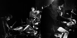 Vier Musiker in dunkler Kleidung spielen auf ihren Instrumenten