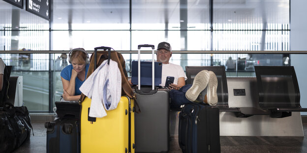 Menschen mit Koffern in Flughafenhalle