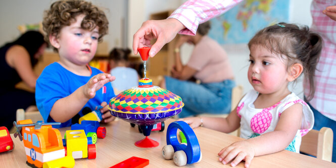 Zwei Kleinkinder spielen an einem Tisch