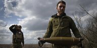 Ukrainische Soldaten tragen Artilleriemunition zu einer Kanone, um russische Stellungen bei Bakhmut zu beschießen