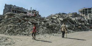 Palästinenser*innen inspizieren die Überreste zerstörter Gebäude in Chan Junis