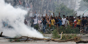 Eine Menschenmenge und brennendes Holz auf den Straßen von Dhaka