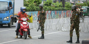 Soldaten kontrollieren Motorradfahrer und Fahrzeuge an einem Checkpoint in Dhaka