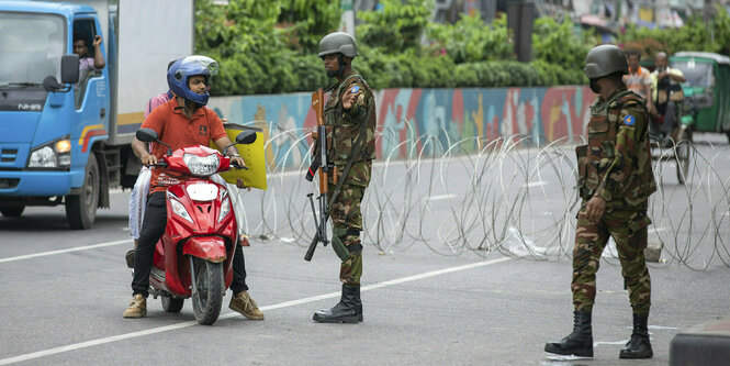 Soldaten kontrollieren Motorradfahrer und Fahrzeuge an einem Checkpoint in Dhaka