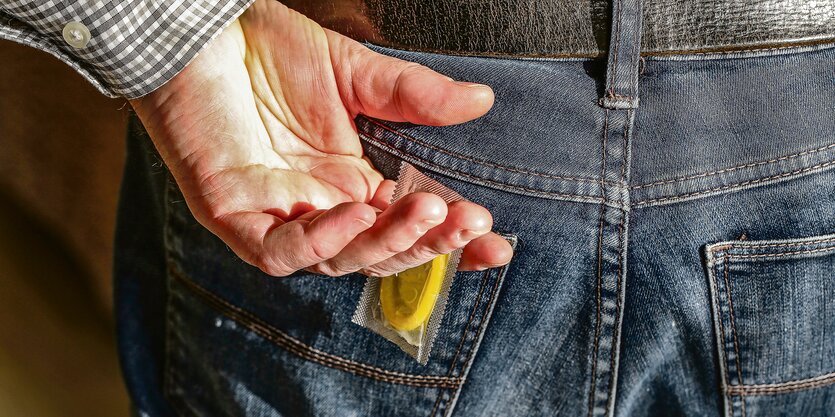 Ein Symbold zum Text über männliche Sexarbeiter: ein Mann hält ein Kondom in einer Hand