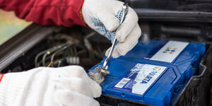 Automechaniker zieht die Klemmen einer Varta-Autobatterie fest