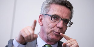 Thomas de Maizière hält seine Zeigefinger hoch