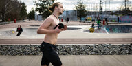 Ein junger Mann joggt oberkörperfrei im Park
