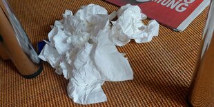 Gebrauchte Papiertaschentücher liegen auf dem Boden