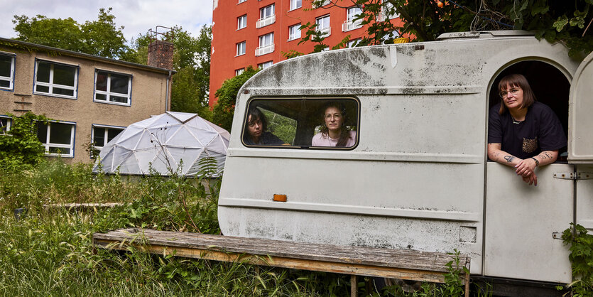 Künstlerinnen verlieren ihr Atelierhaus Heikonaut in Lichtenberg. Ulla, Jana Kreisl (rosa T-Shirt) und Julia Kotowski im Garten der Ateliergemeinschaft, im Hintergrund links das graue Gebäude ist das Atelierhaus. der Wohnwagen ist der Geräteschuppen.