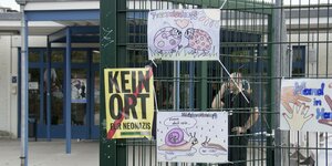 An einem Schultor hängen ein Plakat "Kein Ort für Neonazis" und von Kindern gemalte Bilder