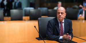 Der Politiker Michael Hartmann sitz an einem Tisch hinter Mikrophonen
