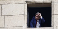 Jean-Luc Melenchon schaut aus dem Fenster eines alten Gebäudes und ballt die Faust
