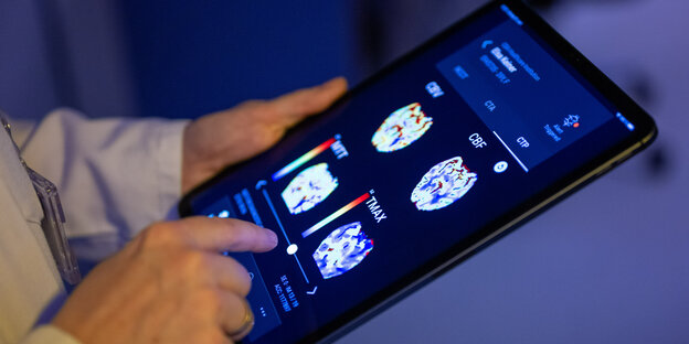 35871751.jpg Eine Radiologin im Unfallkrankenhaus Berlin betrachtet in einer KI-basierten App auf einem Tablet Gehirnbilder eines Patienten
