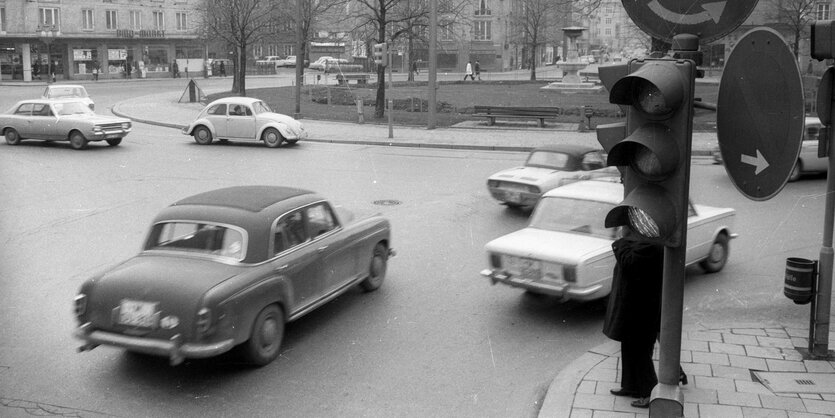 Autos fahren um einen Kreisverkehr. Das Foto ist in Schwarz-Weiß.