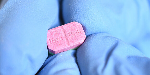 Sterile Handschuhe halten eine Tablette, auf der steht "Red Bull"