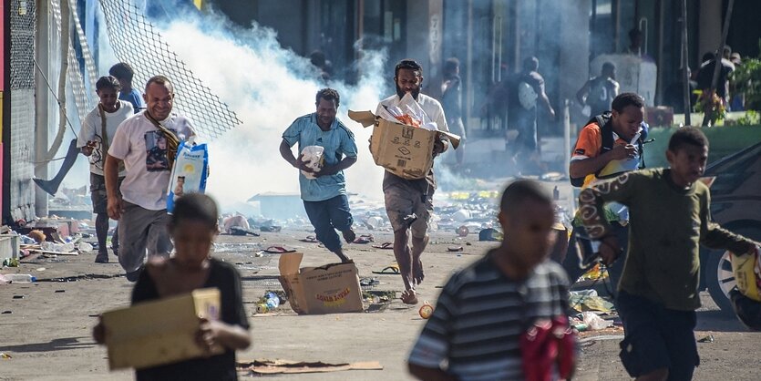 Menschen rennen, Rauch steigt auf, eine Straßenszen aus der Hauptstadt von Papua-Neuguinea