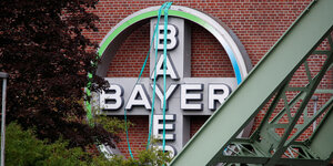 Das Logo der Bayer AG vor einer braunen Hauswand