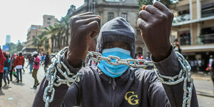 Kenia, Nairobi: Ein Demonstrant, dem beide Hände mit einer Kette gefesselt sind, nimmt an einer Demonstration gegen die Regierung teil.