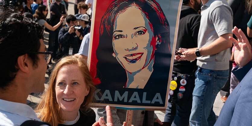 Eine Frau hält eine Plakat mit dem Konterfei von Kamala Harris