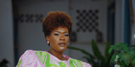 Potrait einer Schwarzen Frau mit kurzem Haar, posierend in einem rosa-grünem Gewand