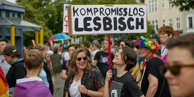 Frauen auf einer Demonstration, eine trägt ein Schild mit der Aufschrift "Kompromisslos lesbisch"