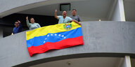 Menschen winken von einem Balkon, der mit der venezolanischen Flagge geschmückt ist