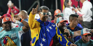 Mit einer weißen Sonnenbrille und in die venezolanische Fahne gehüllt reckt Nicolás Maduro die rechte Hand in die Höhe