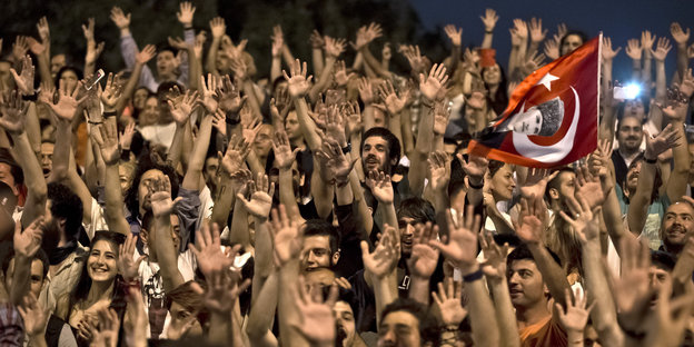 Viele Menschen recken ihre Hände in die Luft, einer schwenkt eine Türkei-Fahne