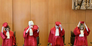 RichterInnen in roten Roben setzen ihre Hüte auf