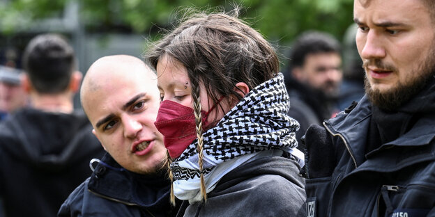 Eine Demonstrantin wird am 7. Mai 2024 in der Freien Universität von zwei Polizisten eskortiert