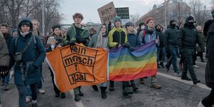 Junge Menschen demonstrieren mit einer Regenbogenfahne