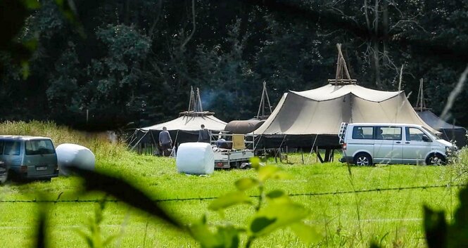 Zelte und Autos stehen auf einer Wiese.