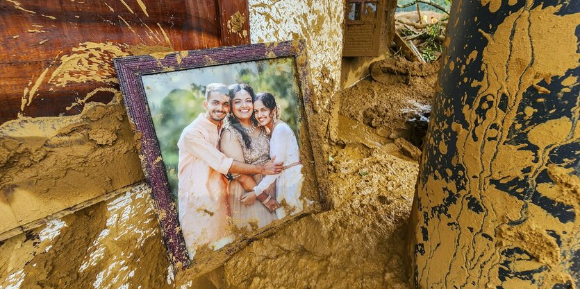 Gerahmtes Familienbild liegt im gelben Schlamm, der durch ein Haus fließt