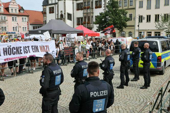 Polizisten bilden eine Reihe vor DemonstrantInnen hinter Absperrung , Plakat "Höcke ist ein Nazi"