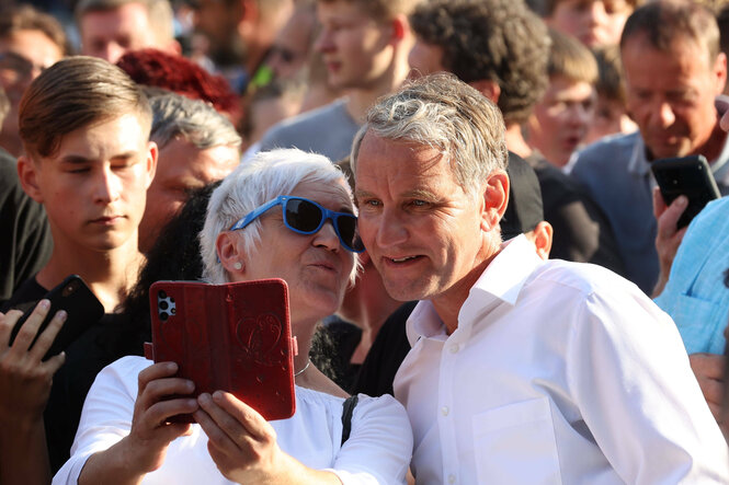 Eine Frau in der Menge macht ein Selfie mit Höcke