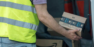 Mann hält ein Amazonpaket in der Hand