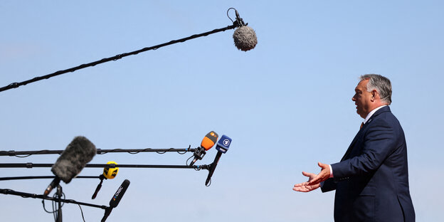 Orban gsteht vor Mikrofonen, die in die Luft ragen
