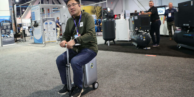 Ein Mann sitzt auf einem elektrisch verstärkten Koffer