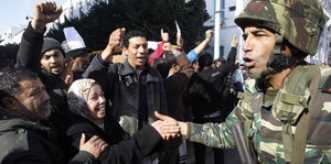 DemonstrantInnen und ein Soldat geben sich auf einer Demonstration die Hand.