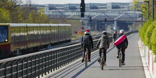 Fahrradfahrende auf einem breiten Weg neben einer Zugtrasse