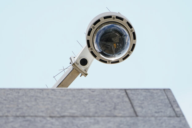 Eine runde Videoüberwachungskamera - von unten fotografiert - ragt über einen Vorsprung.