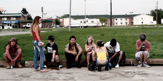 Acht Jugendliche an einem Straßenrand sitzend