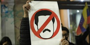 Protest in Buenos Aires gegen Maduro mit einem Plakat das sein Gesicht als Strichzeichnung in einem Stopschild zeigt