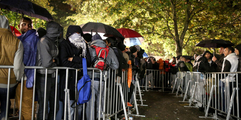 Lange Warteschlangen von Menschen im Regen