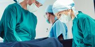 Drei Ärzte in Op-Kleidung während einer Operation