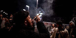 Eine Person raucht auf der Warschauer Brücke in Berlin-Friedrichshain einen übergroßen Joint.