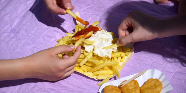 Drei Mädchen teilen sich Pommes Frites mit Ketchup und Mayonaise.