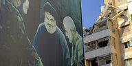Ein Plakat mit dem verstorbenen Hisbollah-Militärkommandeur Imad Mughnijeh (l-r), Hisbollah-Führer Sajjid Hassan Nasrallah und dem verstorbenen General der Revolutionsgarden Kassem Soleimani ist in der Nähe eines beschädigten Gebäudes zu sehen, das bei ei