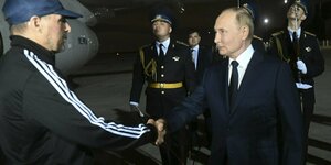 Putin gibt auf dem Flugfeld Krasikov die Hand